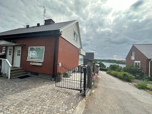 A residential property with a paved driveway, a gated entrance, and a view of a body of water in the background.
