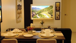 Un coin repas avec une table dressée pour quatre personnes, une grande fenêtre offrant une vue panoramique et un luminaire moderne au plafond.