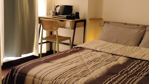 Une chambre à coucher avec un lit, un bureau, une chaise et une lampe.