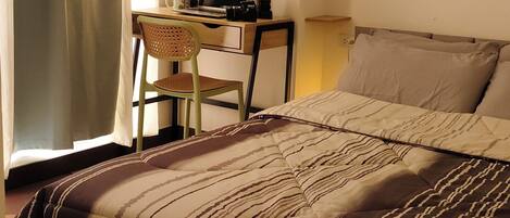 A bedroom with a bed, a desk, a chair, and a lamp.