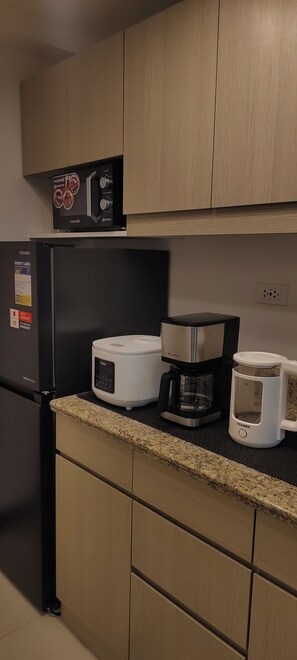 Een keuken met een koelkast, een broodrooster en een koffiezetapparaat op het aanrecht.