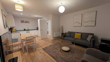 Uma sala de estar moderna com sofá, mesa de centro e área de refeições com cadeiras e mesa.