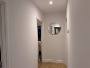 A narrow hallway with a round mirror on the wall, a door leading to a room, and a visible ceiling light. - Comfort and Stylish Nest at Royal Tunbridge Wells (Royal Tunbridge Wells)