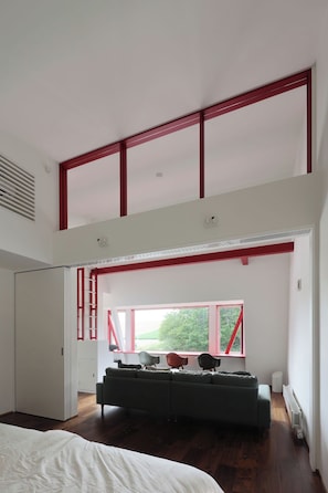 A bedroom with a large bed, a sofa, and a window with a view of greenery. - A Private Villa Nestled Among the Fields of Biei | Accommodates up to 12 Guests—Enjoy BBQs and Bonfires at Villa Hokuto (Kitami)