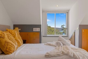 A bedroom with a bed, a window with a view, a wardrobe, and a bedside table. - Luxury Waterfront Retreat with Private Pool (Daleys Point)