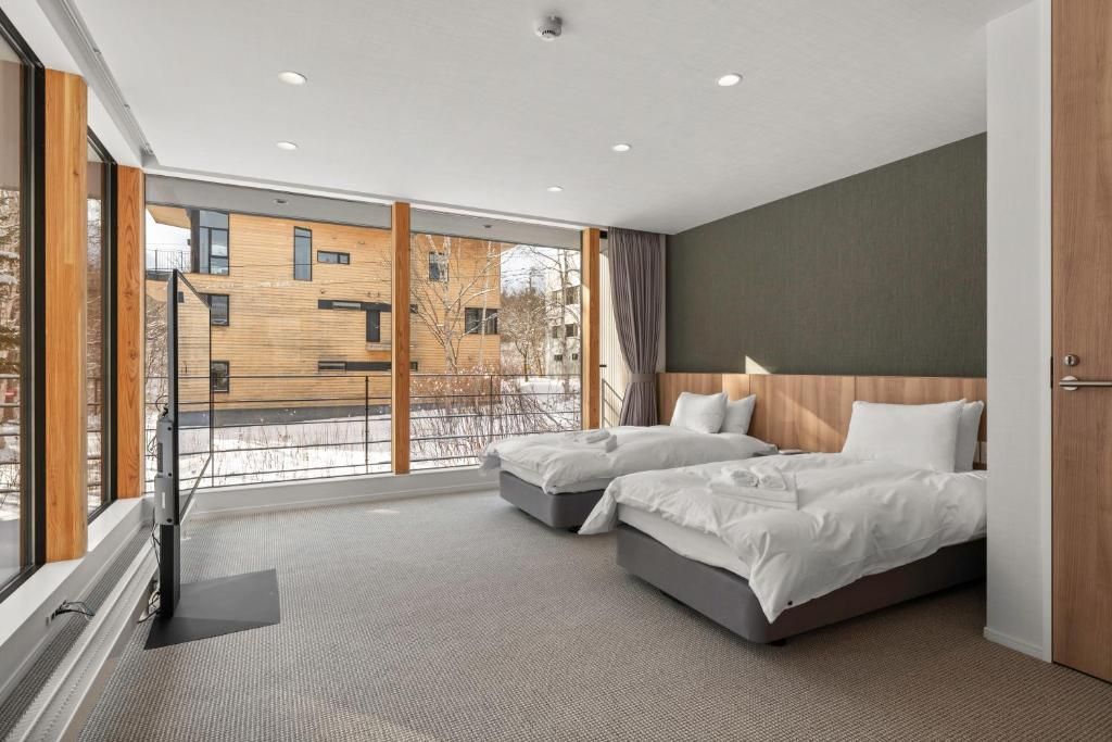 Habitación de hotel con dos camas, un ventanal grande y vista al edificio exterior.