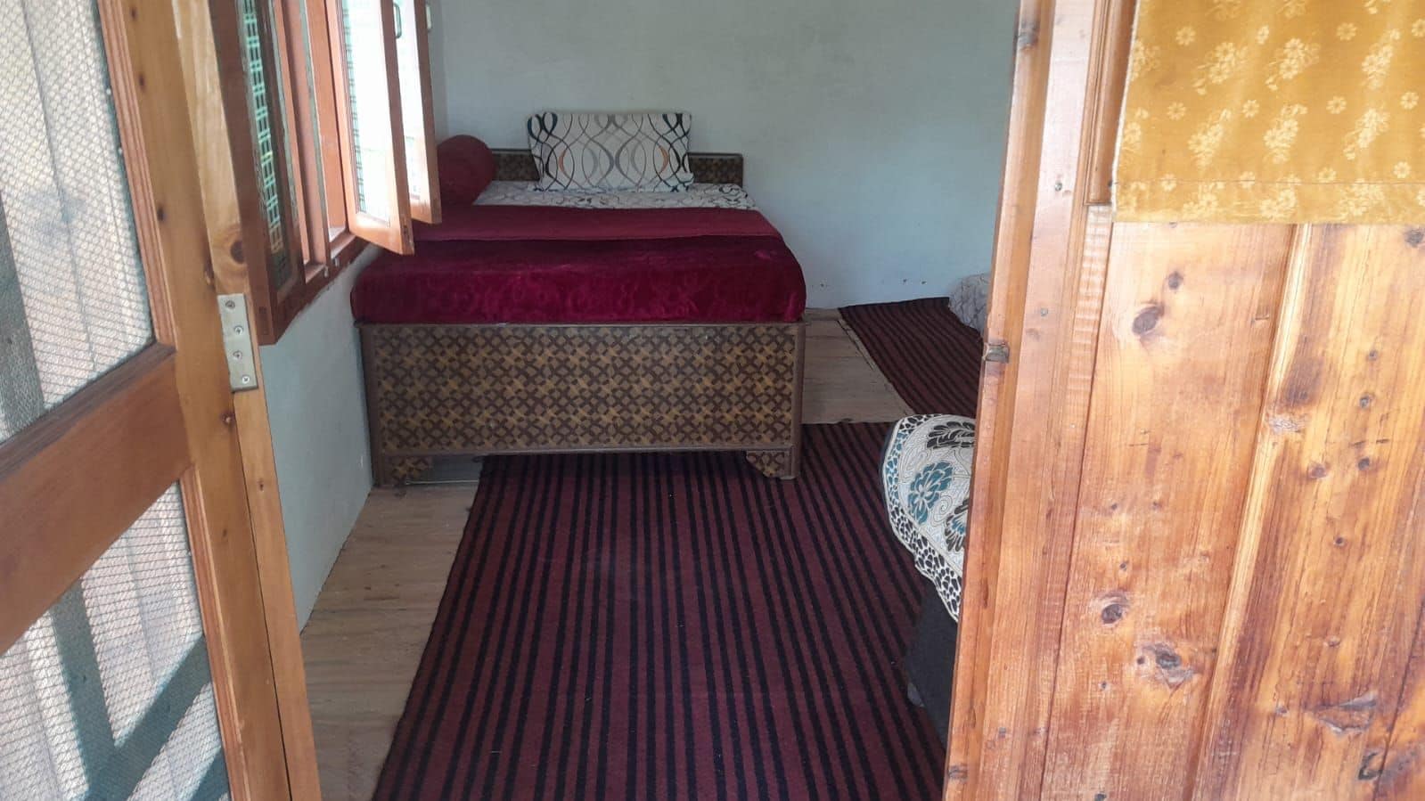 A room with a bed, a patterned wall, and a wooden floor.