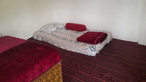 A room with two beds, one with a patterned bedspread and the other with a solid red cover. - Homely Hills,6Km frm Nagtibba trek route (Mayani)