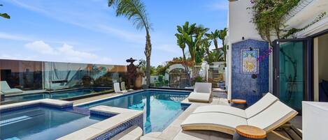 A pool area with lounge chairs and a decorative wall.