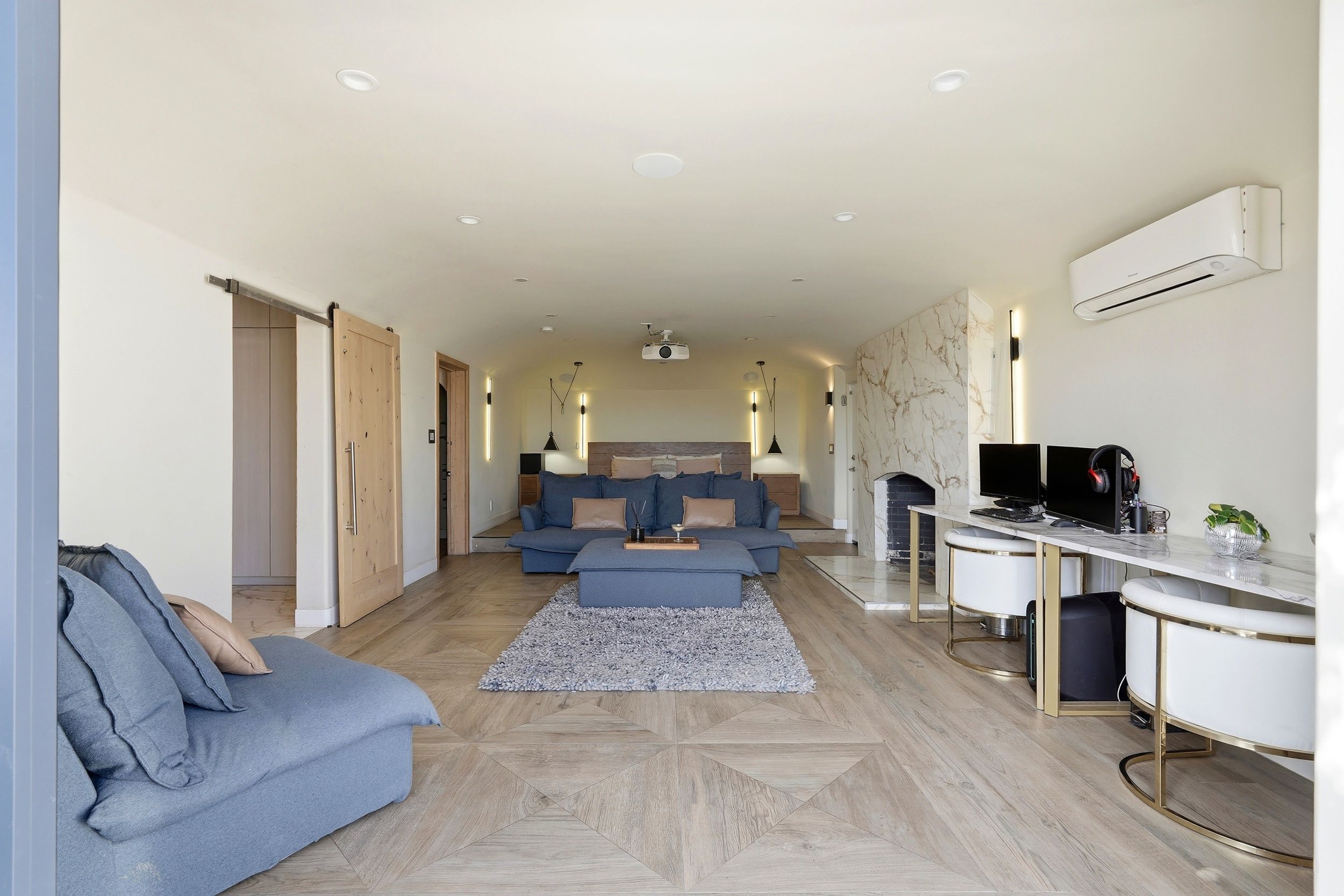 A modern living room with a sofa, a coffee table, a TV, and a desk with a computer.