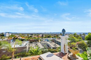 A rooftop terrace with a decorative urn, a view of a cityscape, and a clear sky.