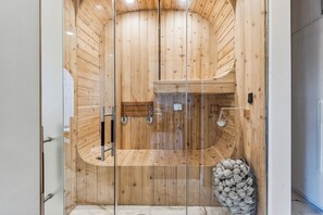 A sauna with wooden walls and a glass door, a bench, and a metal container with stones. - Historic Sunset Strip Suite w/ Pool & Jacuzzi (Los Angeles)