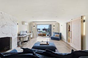 A modern bedroom with a large bed, a desk, and a view of a pool and cityscape.