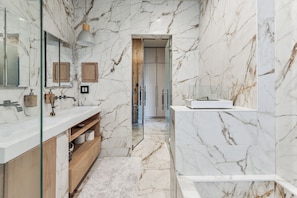 A modern bathroom with marble walls, a glass shower enclosure, and wooden cabinetry.