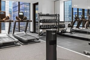 Ein modernes Fitnessstudio mit Laufbändern, Gewichten und einem Schlagring.
