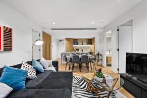 Ein modernes Wohnzimmer mit einer Couch, einem Essbereich und einer Küche im Hintergrund.