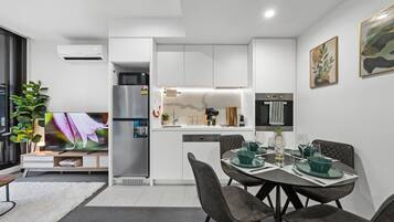 Een moderne keuken met witte kasten, een ingebouwde oven en een eethoek met een tafel voor vier personen.