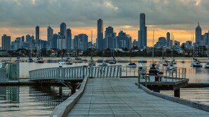 A waterfront cityscape with a marina, docked boats, and a city skyline. - Rooftop Pool Views · Sleek 1BR on St Kilda Rd (Melbourne)