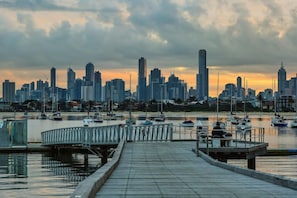 A waterfront cityscape with a marina, docked boats, and a city skyline. - Rooftop Pool Views · Sleek 1BR on St Kilda Rd (Melbourne)