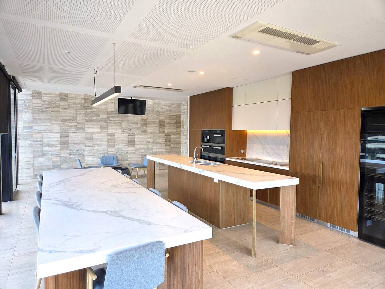 A modern kitchen with a marble countertop, wooden cabinets, and a built-in oven.