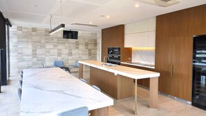 A modern kitchen with a marble countertop, wooden cabinets, and a built-in oven. - Rooftop Pool Views · Sleek 1BR on St Kilda Rd (Melbourne)