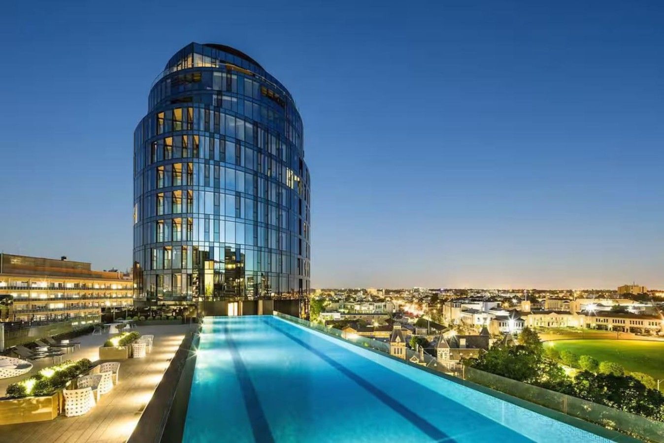 Een modern hotel met een gebogen glazen gevel, een dakzwembad en uitzicht op de omliggende stad.