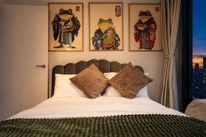 Ein Hotelzimmer mit einem Bett, zwei Kissen und drei gerahmten Kunstwerken an der Wand.
