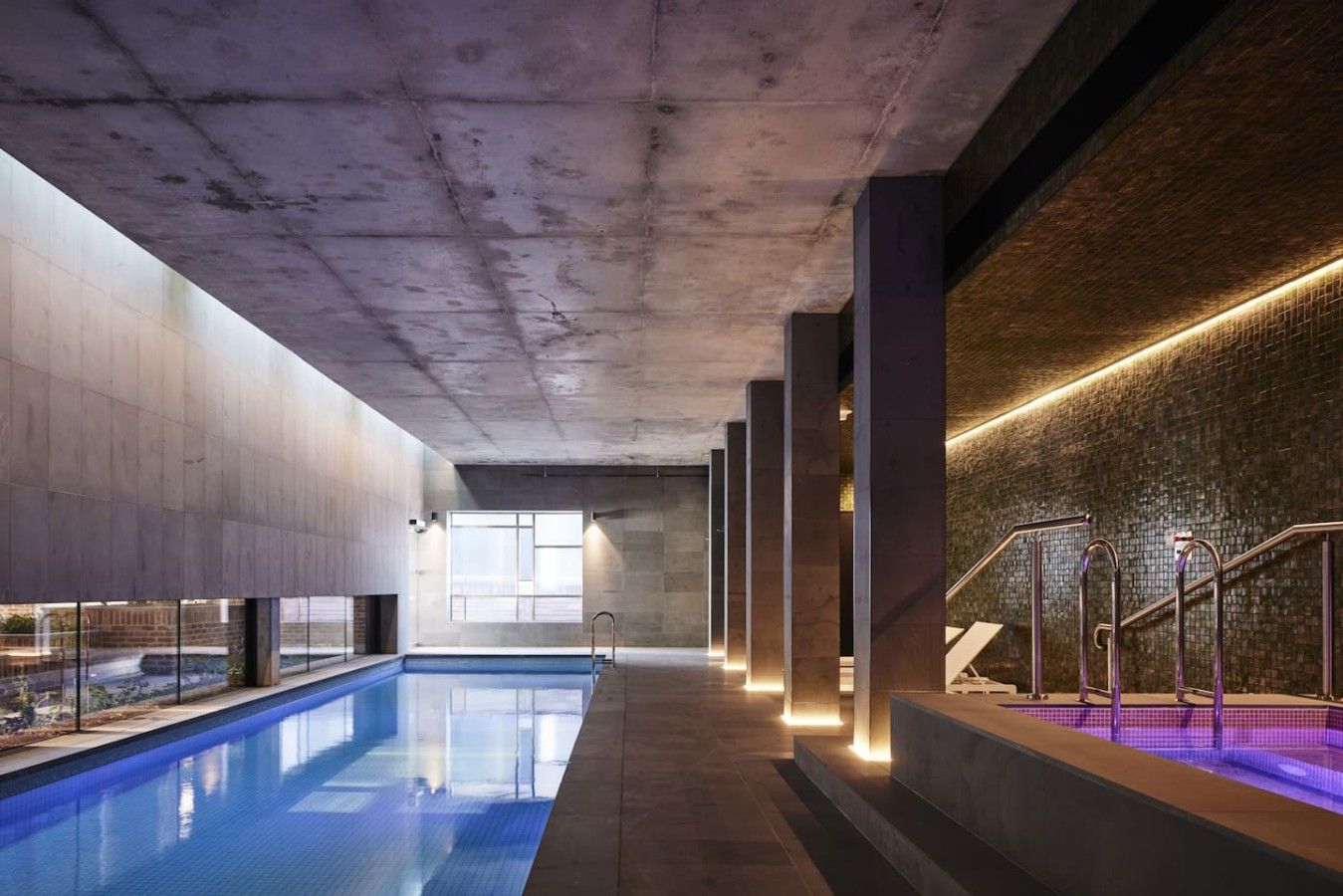 Ein moderner, überdachter Pool mit freier Sicht, einer Treppe und einer Ziegelwand.
