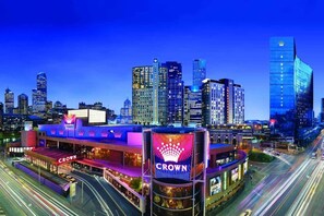 A cityscape with a prominent building featuring the 'Crown' sign, surrounded by high-rise buildings and busy streets. - Golden Hour · 2BR · Level 42 Skyline + Pool (Melbourne)