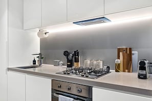 A modern kitchen with a gas stove, a built-in oven, and a stainless steel countertop. - Designer 2BR · Heart of CBD · Pool + Free Trams (Melbourne)