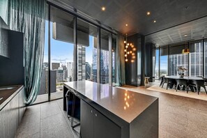 A modern interior with a large window, a central island, and a dining area. - Designer 2BR · Heart of CBD · Pool + Free Trams (Melbourne)