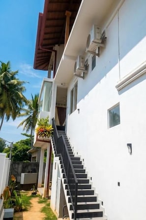 A white building with a staircase leading to a balcony.