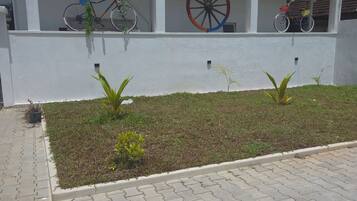 A building with a balcony, a bicycle, and a wheelbarrow.