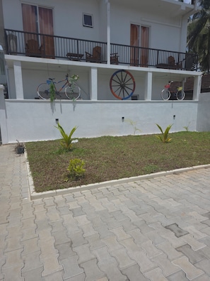 A building with a balcony, a bicycle, and a wheelbarrow.