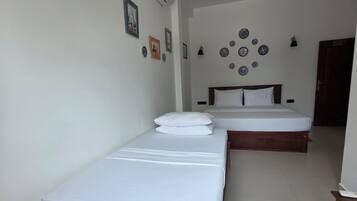 A hotel room with two single beds, a ceiling fan, and a wall-mounted air conditioner.