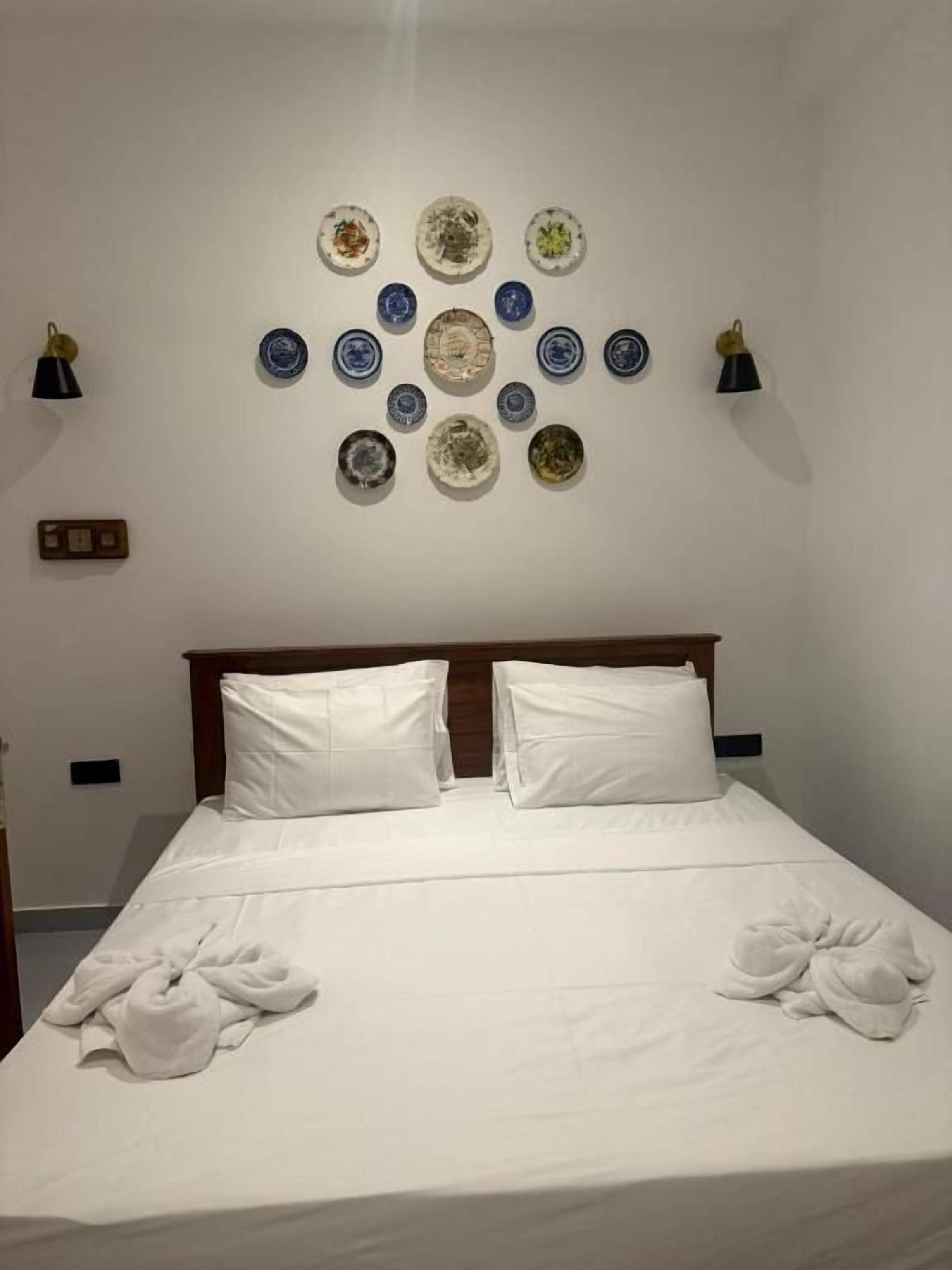A hotel room with a neatly made bed, a wall-mounted plate display, and two bedside lamps.