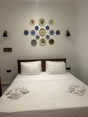 Una habitación de hotel con una cama bien hecha, un expositor de platos en la pared y dos lámparas de noche.