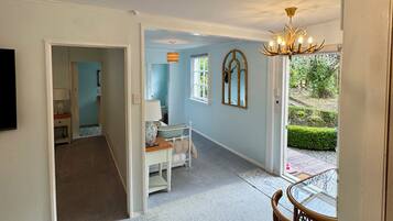 A spacious room with a chandelier, a dining table, and a view of a garden.