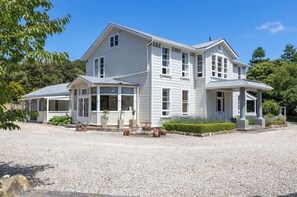 Une maison à deux étages avec un porche couvert, une allée en gravier et un jardin bien entretenu.