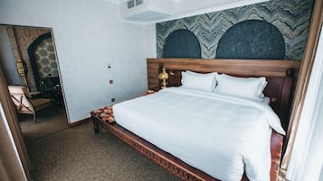 Quarto de hotel com uma cama grande, cabeceira de madeira e parede estampada.