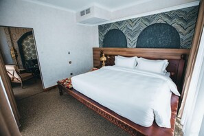 Una habitación de hotel con una cama grande, cabecera de madera y pared con estampado.