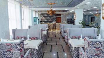 Een restaurant met zitplaatsen in hokjes, een bar en een plafond met patroon.