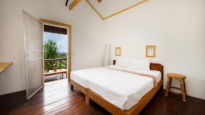Een slaapkamer met een houten bed, een klein krukje en een balkon met planten.