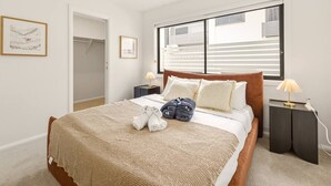 A bedroom with a bed, a ceiling fan, a window with blinds, a nightstand with a lamp, and a door leading to a closet. - BrandNew|DuctedAC|Walk to Train&Shop|Double Garage (Oxley)