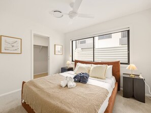 A bedroom with a bed, a ceiling fan, a window with blinds, a nightstand with a lamp, and a door leading to a closet. - BrandNew|DuctedAC|Walk to Train&Shop|Double Garage (Oxley)