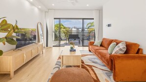 A modern living room with a sofa, coffee table, and TV on a wooden cabinet. - BrandNew|DuctedAC|Walk to Train&Shop|Double Garage (Oxley)