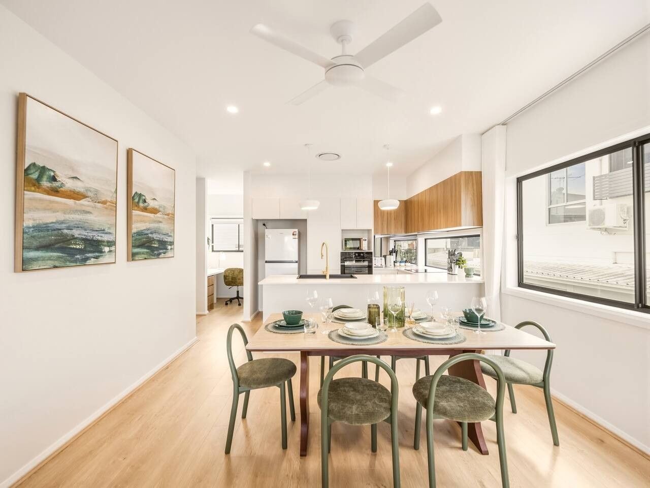 A modern kitchen with white cabinets, a central island, and a dining area with a table set for four.