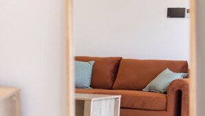 A room with a brown sofa, a small wooden side table, and a white rug. - BrandNew|DuctedAC|Walk to Train&Shop|Double Garage (Oxley)