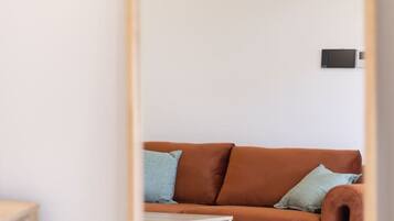 A room with a brown sofa, a small wooden side table, and a white rug.