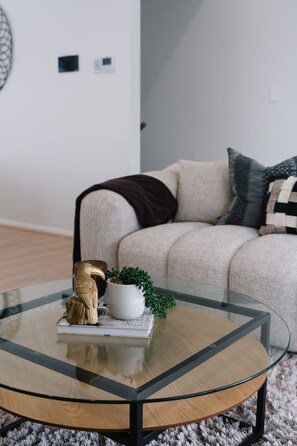 Una sala de estar moderna con una mesa de centro de vidrio, un sofá y objetos decorativos.
